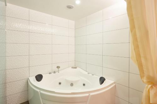 a white bath tub in a white tiled bathroom at DREAM LUXURY HOTEL in Muar