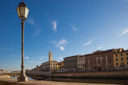 a street light next to a river with buildings at Hotel Terminus & Plaza in Pisa