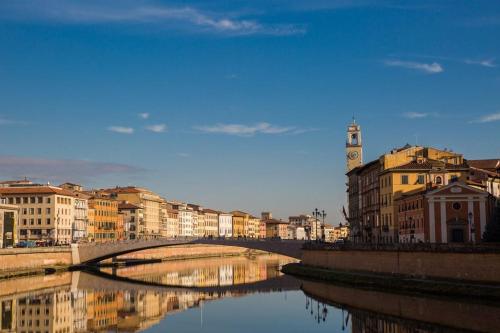 a bridge over a river with buildings and a clock tower at Hotel Terminus & Plaza in Pisa