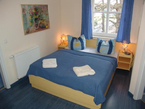 a bedroom with a blue bed with two towels on it at Apartments Villa Seeblick in Baabe