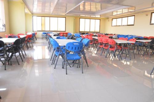 a room filled with tables and chairs with red and blue chairs at Tigers's apartment Hotel in Bujumbura