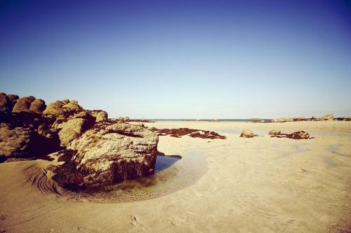 a large rock on a sandy beach with the ocean at Hôtel Les Coutainvillaises in Agon Coutainville
