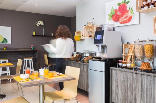 a woman is standing behind a counter in a restaurant at Aparthotel Adagio Access Strasbourg Illkirch in Illkirch-Graffenstaden