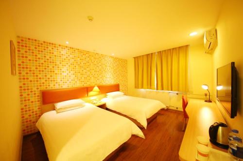 una camera d'albergo con 2 letti e una scrivania di Home Inn Zhengzhou Huanghe Road Provincial People's Hospital a Zhengzhou