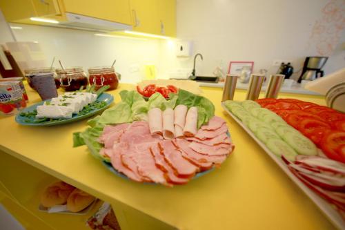 a counter topped with plates of meat and vegetables at eMKa Hostel in Warsaw