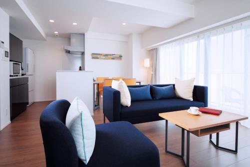 Oakwood Apartments Nishi-Shinjuku في طوكيو: غرفة معيشة مع أريكة زرقاء وطاولة