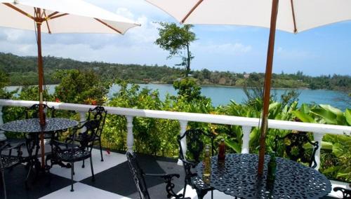 a balcony with tables and chairs and a view of a river at Jamaica Palace Hotel in Port Antonio