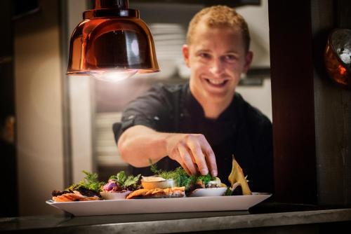 a man preparing a plate of food on a table at Flåmsbrygga Hotel in Flåm