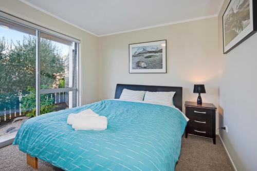 納爾遜的住宿－Above The Cut，一间卧室设有蓝色的床和窗户。