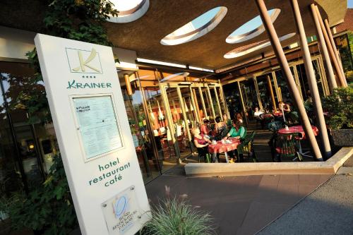a sign in front of a restaurant with people sitting at tables at Hotel-Restaurant-Café Krainer in Langenwang