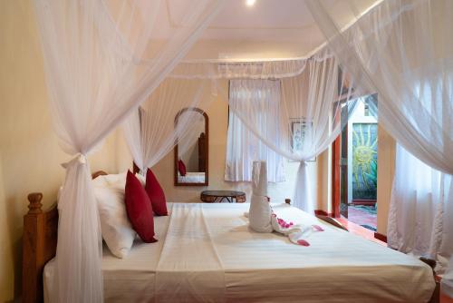 a bedroom with a canopy bed with white curtains at Chandra Villa Ayurveda Resort in Bentota