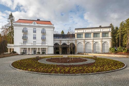 a large white building with a clock in front of it at Hotel SPA Dr Irena Eris Polanica Zdrój in Polanica-Zdrój