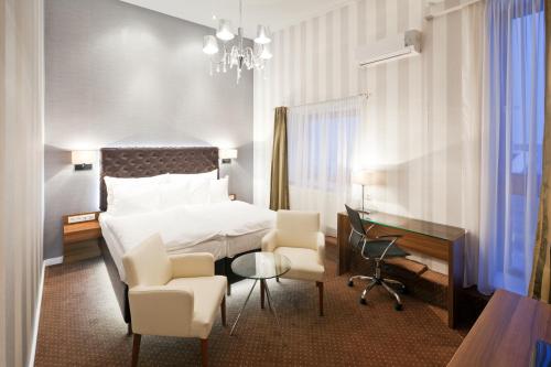 um quarto de hotel com uma cama, uma escrivaninha e cadeiras em Pytloun City Boutique Self Check-in Hotel em Liberec