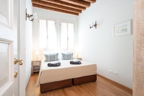 una camera da letto con un letto con lenzuola bianche e cuscini blu di Casa Claudia ai Frari a Venezia