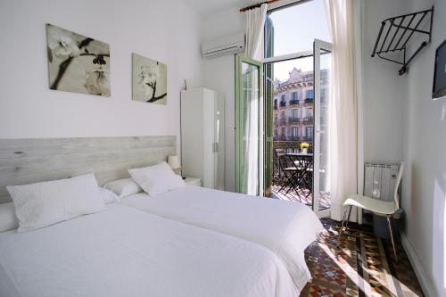 1 dormitorio blanco con 2 camas y ventana en Hostal Eixample, en Barcelona