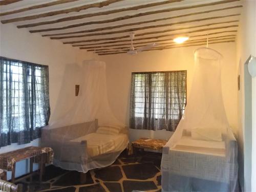 a bedroom with two beds and two windows at Sheba Cottages - Diani Beach in Diani Beach