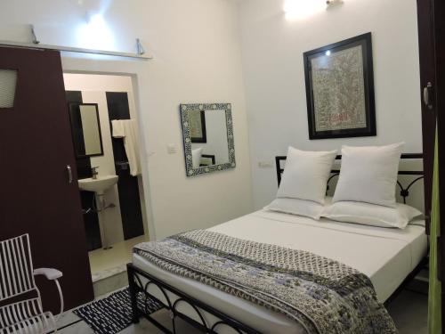 a bedroom with a bed with white pillows and a mirror at Hotel Mewari Villa PURE VEG in Udaipur