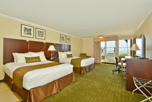 a hotel room with two beds and a desk at Best Western Plus Dana Point Inn-by-the-Sea in Dana Point