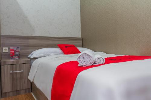 uma cama branca com toalhas vermelhas e brancas em RedDoorz Plus near IPDN em Sumedang