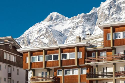 a hotel with snow covered mountains in the background at HelloCHALET - Maison Rêve Blanc - Ski to door with Matterhorn view in Breuil-Cervinia
