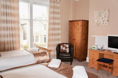 een slaapkamer met 2 bedden, een stoel en een televisie bij Camillia Guest House in Aberdeen