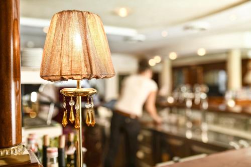 a lamp in a bar with a person in the background at Hotel MARIA THERESIA adults-only in Lagundo