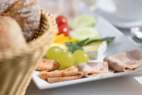 a plate of food with meat and grapes and bread at Hotel MARIA THERESIA adults-only in Lagundo