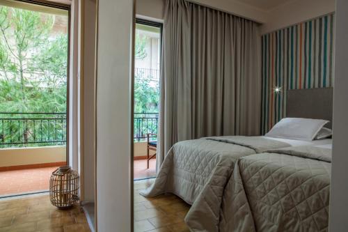 a bedroom with a bed and a balcony at Pitsakis Hotel in Tolo