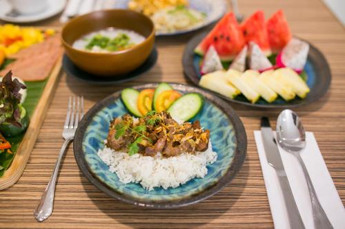 a table topped with plates of food with rice and fruit at Lanna Thaphae Hotel in Chiang Mai
