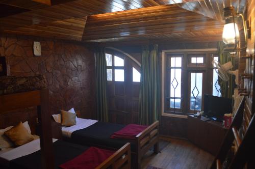 a small room with two beds and a television at Quinton Enclave in Shillong