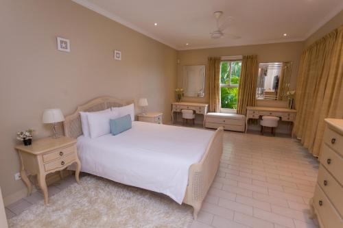 a bedroom with a large white bed and a bathroom at Eden Island Luxury Two Bedroom Apartment in Mahe