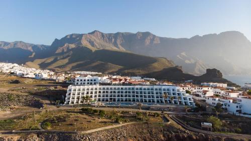 a large white building in front of a mountain at Occidental Roca Negra - Adults Only in Agaete