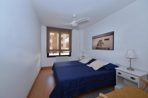 a bedroom with a blue bed and a window at Apartamento CERCA PLAYA CON BALCON Y BBQ in Calafell