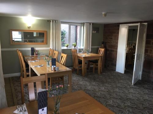 a dining room with wooden tables and chairs and windows at The Kellbank in Gosforth