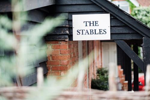 a sign on the side of a building that reads the stables at Bel and The Dragon-Odiham in Odiham