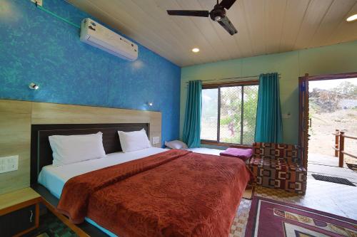 a bedroom with a large bed with blue walls at Forest Eco Lodge in Mount Ābu
