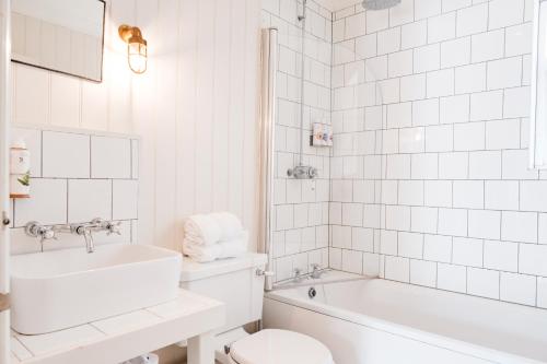 a white bathroom with a sink and a toilet and a tub at Bel and The Dragon-Odiham in Odiham