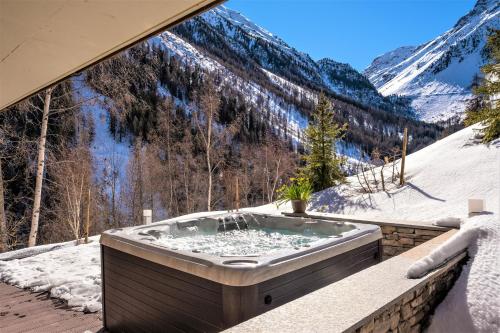 a jacuzzi tub on a balcony with a snowy mountain at Chalet Les Rahâs by Mrs Miggins in Grimentz