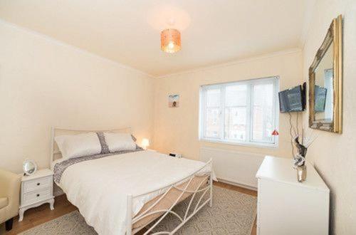 1 dormitorio con cama y ventana en TDM Bachelot Lettings Ltd en Londres