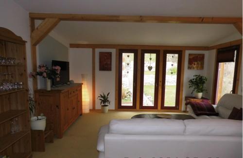 a living room with a white couch and windows at Ferienwohnung Kirchbergblick in Thale