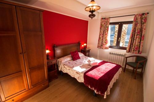 a bedroom with a bed and a red wall at Apartamentos Las Palmeras in Cangas de Onís