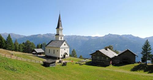 a church on a hill with mountains in the background at Erholungshotel Margarethenbad in Rangersdorf