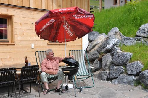an older man sitting in a chair under an umbrella at Lechtaler Naturparkchalets in Gramais