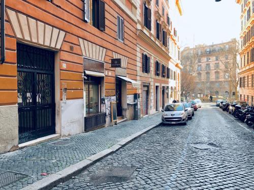 a cobblestone street with cars parked next to buildings at Roma Trasteverina in Rome