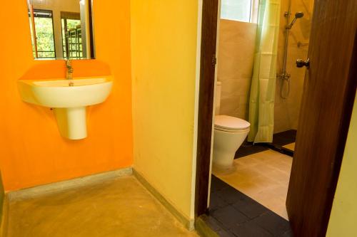 a bathroom with a toilet and a sink and a mirror at Bunk Station in Ella