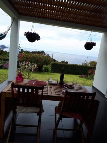 a table and chairs on a porch with a view of the ocean at Casa da Ribeira in Lajes do Pico