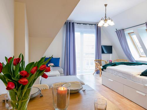 a bedroom with a bed and a table with flowers at VacationClub - Armii Krajowej Apartament 10 in Kołobrzeg