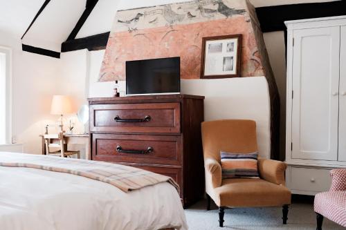 a bedroom with a bed and a tv and a chair at Bel and The Dragon-Odiham in Odiham