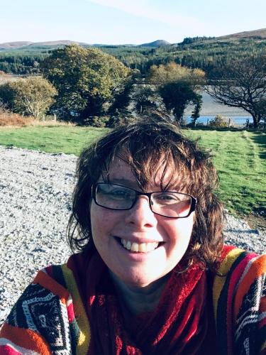 a woman wearing glasses is smiling for the camera at Annie's River Retreat in Doochary