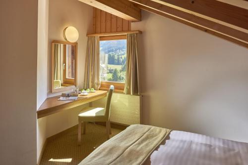 1 dormitorio con escritorio, 1 cama y ventana en Hostellerie am Schwarzsee, en Bad-Schwarzsee